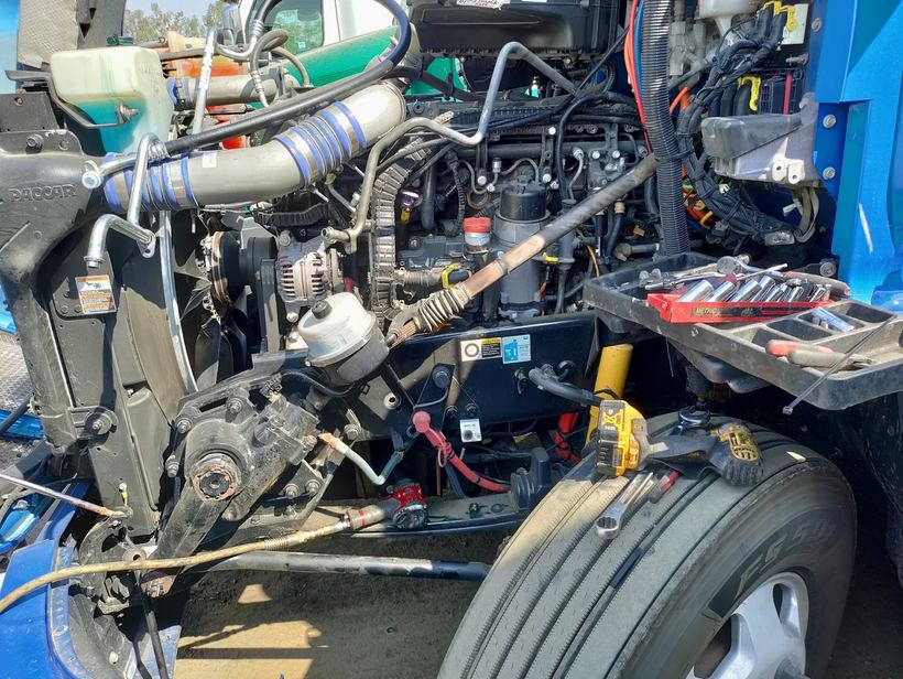 A semi truck's engine bay opened up for an air conditioning repair